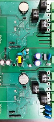 The dual energy meter board: a green PCB with two mirrored measurement sections, bulk capacitors, and pin headers along one edge for panel wiring.