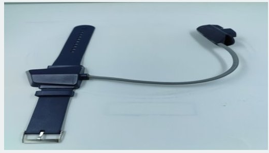 The wearable tracker: a navy wrist strap with the device housing on the band, tethered by a short grey cable to a separate clip-on sensor.